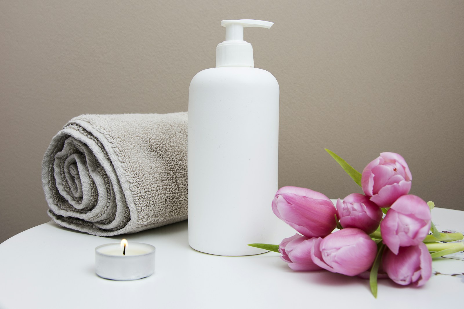 Flowers, a candle, lotion, and a towel in a spa still life